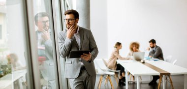 Ofiste dijital tablet kullanan yakışıklı genç iş adamı.