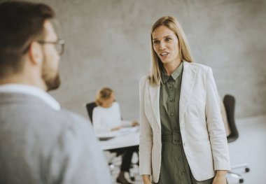 Genç erkek ve kadın iş çifti ofiste genç insanlarla iş konuşuyorlar.
