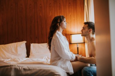 Pencerenin yanındaki odada sevişen ve sarılan çift.