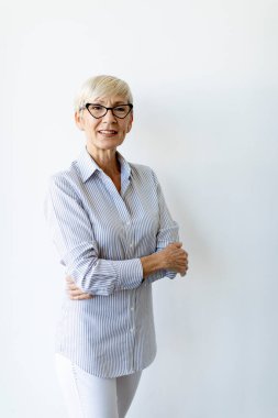 Ofisin duvarında kollarını kavuşturmuş, olgun bir iş kadını.