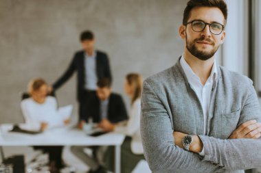 Yakışıklı genç iş adamı ekibinin önünde kendinden emin duruyor.