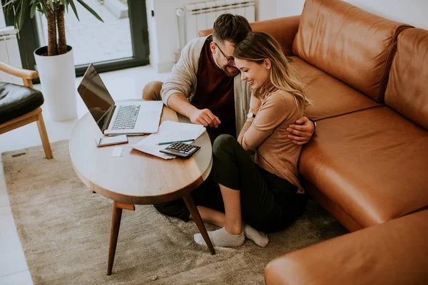 Genç kadın ve genç adam evdeki kanepede otururken dizüstü bilgisayar kullanıyorlar.