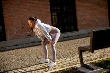 Yorgun genç bir kadın şehir ortamında eğitim sırasında dinleniyor.