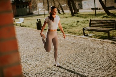 Şehir ortamında eğitim sırasında esneme hareketleri yapan güzel bir genç kadın.