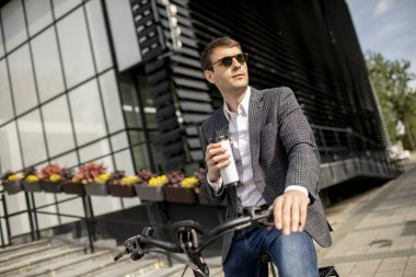 Bisikletli yakışıklı genç işadamı kahve fincanı getirmiş.