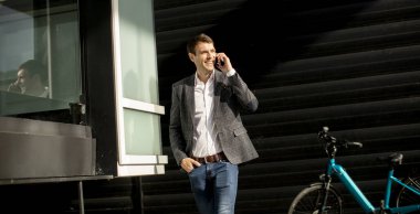 Bisikletten inip cep telefonu kullanan yakışıklı bir iş adamı.