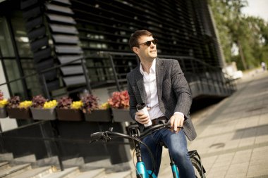 Bisikletli yakışıklı genç işadamı kahve fincanı getirmiş.