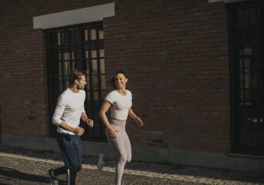 Şehir ortamında koşan yakışıklı genç çift.