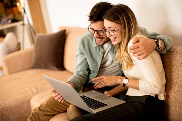 Bonito Jovem Casal Usando Laptop Juntos Enquanto Sentado Sofá Casa — Fotografia de Stock