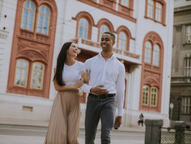 Sokakta yürüyen yakışıklı, etnik çeşitlilikte genç bir çift.