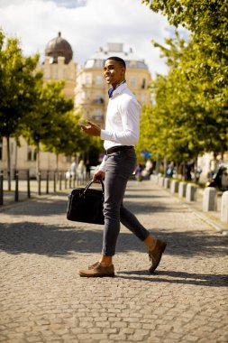 Yakışıklı Afro-Amerikan iş adamı bir caddeyi kapatırken cep telefonu kullanıyor.