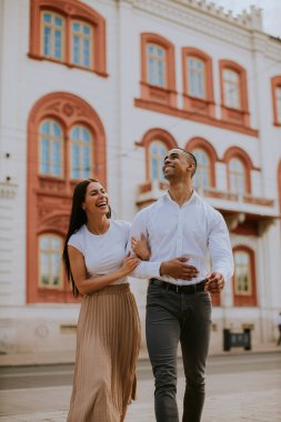 Sokakta yürüyen yakışıklı, etnik çeşitlilikte genç bir çift.