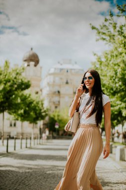 Sokakta yürürken cep telefonu kullanan güzel bir genç kadın.