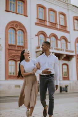Sokakta yürüyen yakışıklı, etnik çeşitlilikte genç bir çift.