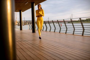 Güzel genç bayan nehir kenarında koşuya çıkıyor.