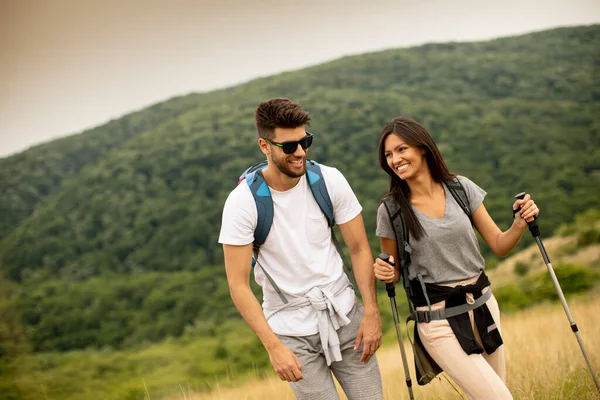 Uśmiechnięta Młoda Para Spacerująca Plecakami Zielonych Wzgórzach Letni Dzień — Zdjęcie stockowe