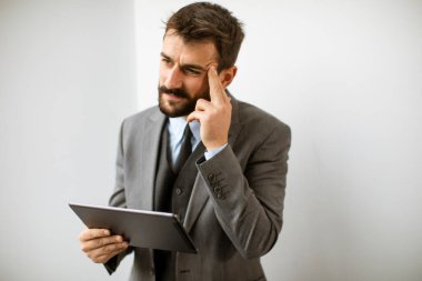 Ofiste dijital tablet kullanan yakışıklı genç iş adamı.