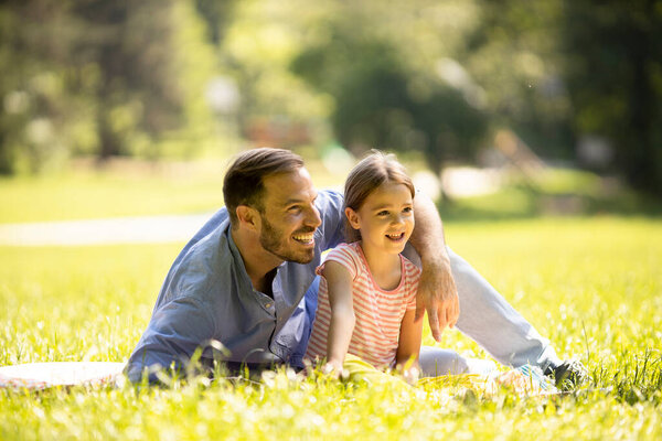 Отец с милой маленькой дочкой веселится на траве в парке