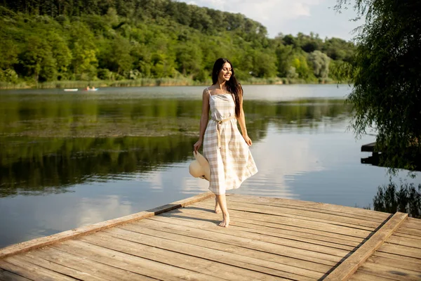 穏やかな湖で木製の桟橋に立つ若い女性をリラックス — ストック写真