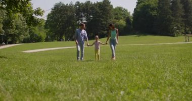 Küçük tatlı kızıyla mutlu bir aile güneşli bir günde parkta eğleniyor.