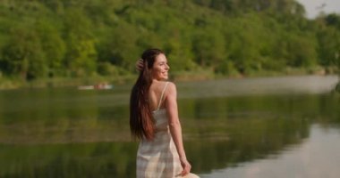 Sakin gölün kıyısındaki ahşap iskelede yürüyen rahatlatıcı genç kadın.