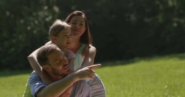 Glückliche junge Familie mit süßer kleiner Tochter, die an einem sonnigen Tag Spaß im Park hat — Stockvideo