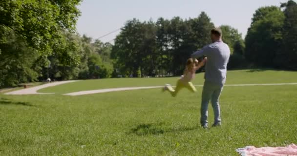 Отец с милой маленькой дочкой веселится на траве в парке — стоковое видео