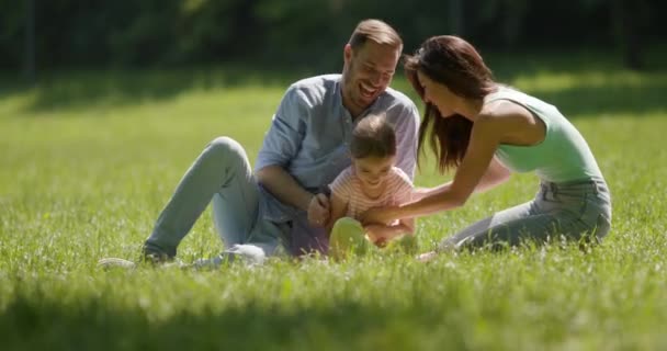 Felice giovane famiglia con carina figlioletta divertirsi nel parco in una giornata di sole — Video Stock