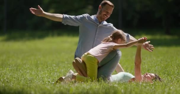 在阳光灿烂的日子，快乐的年轻家庭和可爱的小女儿在公园里玩得开心 — 图库视频影像