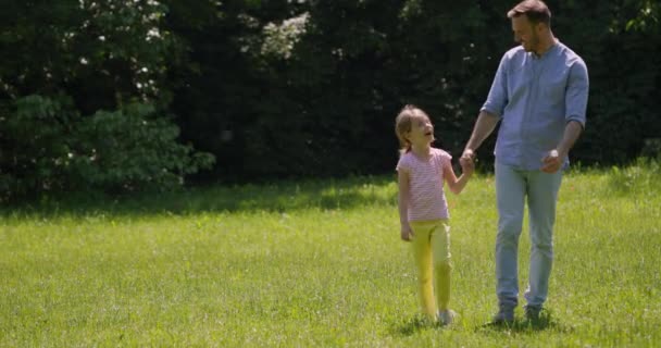 Padre con linda hija divirtiéndose en la hierba en el parque — Vídeo de stock