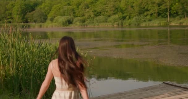 Расслабляющая молодая женщина бежит на деревянном пирсе у спокойного озера — стоковое видео