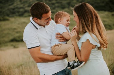 Genç bir aile ve küçük tatlı bir çocuk yaz tarlasında eğleniyorlar.