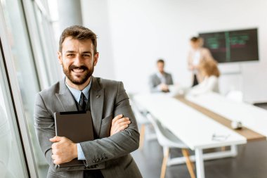 Ofiste dijital tablet kullanan yakışıklı genç iş adamı.