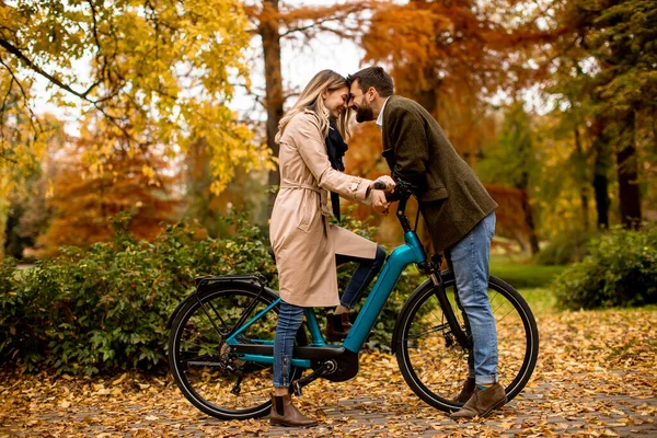 美丽的年轻夫妇在秋天的公园里骑着电动自行车 — 图库照片