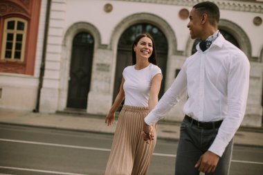 Sokakta yürüyen yakışıklı, etnik çeşitlilikte genç bir çift.