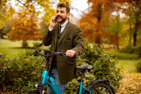 Przystojny Młodzieniec Korzystający Telefonu Komórkowego Rowerze Elektrycznym Jesiennym Parku — Zdjęcie stockowe