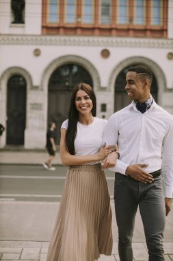 Sokakta yürüyen yakışıklı, etnik çeşitlilikte genç bir çift.