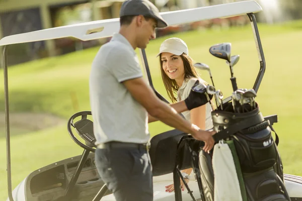 Pareja joven en carrito de golf — Foto de Stock