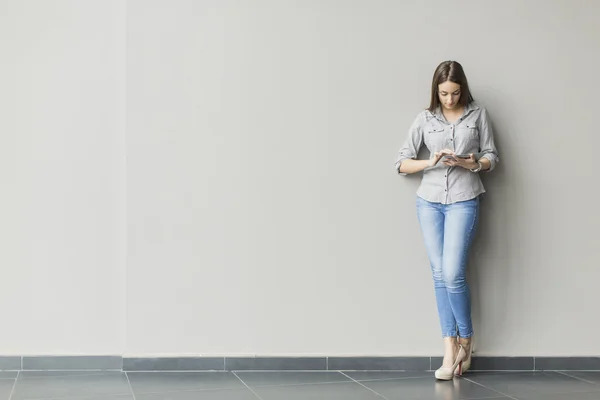 Woman with tablet by the wall — Stock Photo, Image