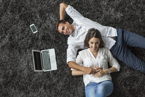 Pareja joven relajándose en la alfombra — Foto de Stock