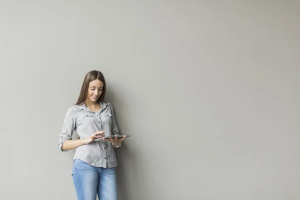 Vrouw met tablet door de muur — Stockfoto