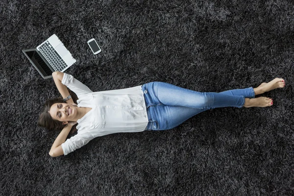 Mujer joven relajándose en la alfombra —  Fotos de Stock