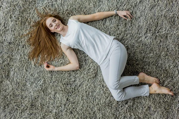 Mujer acostada en la alfombra — Foto de Stock