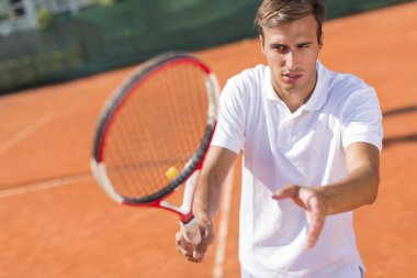 Genç adam tenis oynuyor.