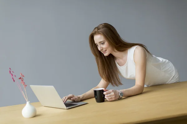 Νεαρή γυναίκα με φορητό υπολογιστή στο γραφείο — Φωτογραφία Αρχείου
