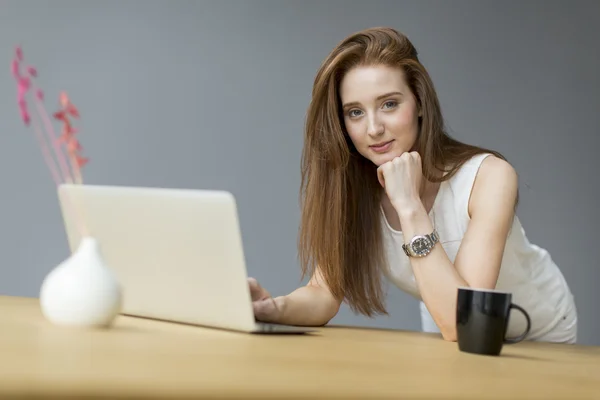 Νεαρή γυναίκα με φορητό υπολογιστή στο γραφείο — Φωτογραφία Αρχείου