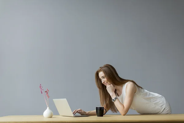 Jeune femme avec ordinateur portable dans le bureau — Photo