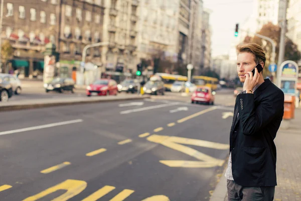 Молодой человек на улице с мобильным телефоном — стоковое фото