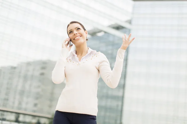 Young business woman talking on mobile phone in front of office — Stock Photo, Image