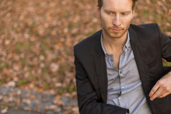 Молодой человек на скамейке в осеннем парке
